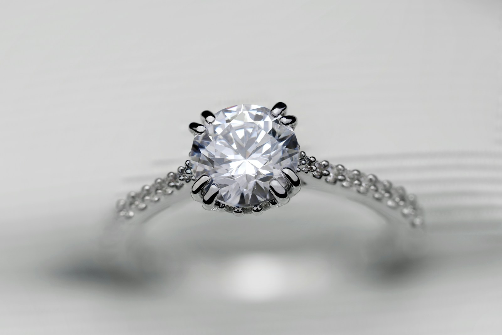 Light catching the facets of a brilliant-cut diamond and its polished setting